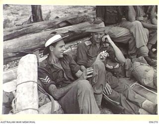 JACQUINOT BAY, NEW BRITAIN. 1945-09-09. SERGEANT K.T. CARMODY (1) AND LIEUTENANT A.F. GREENING (2) MEMBERS OF 55 FIELD PARK COMPANY, WAITING TO EMBARK ON THE HMAS MANOORA. THE MANOORA CARRIED ..