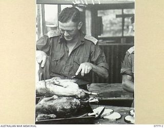 BOUGAINVILLE ISLAND. 1944-12-25. QX36029 CAPTAIN W.L. RUDDER, 61ST INFANTRY BATTALION, CARVING UP A TURKEY FOR THE TROOPS ON CHRISTMAS DAY