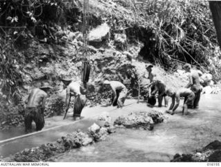 Finschhafen Area, New Guinea. 1943-10. Engineers dig out a creek to make foundations for a bridge on the main track from Finschhafen to foward areas