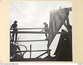 WIRUI BEACH, WEWAK, NEW GUINEA. 1945-09-04. PRIVATE K. SAYERS (1) AND PRIVATE R. FRIESSLONG (2), MEMBERS OF 2/11 INFANTRY BATTALION SILHOUETTED AGAINST THE SKYLINE AS THEY WORK ON A NEW BUILDING