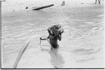 Schrader Range: man carries cargo across Anjimamp River between Korumbon and Ambaiat