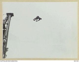 PORT MORESBY, NEW GUINEA. 1943-11-28. A COMPETITOR DOING A JACKNIFE DIVE IN THE HIGH DIVING COMPETITION A THE ALLIED SERVICES GRAND SWIMMING CARNIVAL