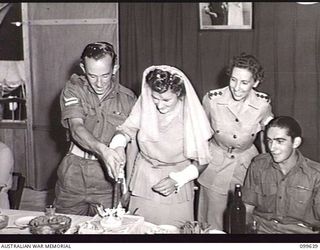 RABAUL, NEW BRITAIN, 1946-01-05. CORPORAL R. STANLEY, AUSTRALIAN MOVEMENT CONTROL, AND HIS BRIDE, FORMERLY PRIVATE BARBARA JAMES, AUSTRALIAN ARMY MEDICAL WOMEN'S SERVICE (AAMWS), CUTTING THEIR ..