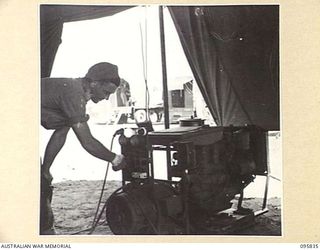 CAPE WOM, WEWAK AREA, NEW GUINEA. 1945-08-30. CORPORAL A.J. HARRISON AT 2/4 ARMOURED REGIMENT WORKSHOP, CORPS OF AUSTRALIAN ELECTRICAL AND MECHANICAL ENGINEERS, WORKING ON A JAPANESE GENERATOR