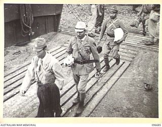 KAIRIRU ISLAND, NEW GUINEA. 1945-09-17. JAPANESE NAVAL OFFICERS EMBARKING ON BARGE FOR TRANSFER TO MUSCHU ISLAND. AMONG THEIR BELONGINGS MANY HAD CHICKENS AND FOWLS WHICH WERE CARRIED IN VARIOUS ..