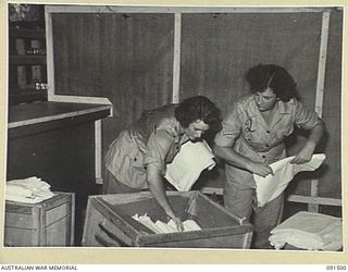 LAE, NEW GUINEA. 1945-05-07. PRIVATE G.E. KIRLEY (1) AND CORPORAL E.C. NELSON (2), UNPACKING SHEETS WHICH HAVE BEEN ISSUED TO ALL RANKS OF THE AUSTRALIAN WOMEN'S ARMY SERVICE IN THEIR NEW QUARTERS ..