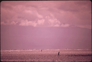 FISHERMEN IN SURF ON THE ISLAND'S EASTERN SHORE. IN THE BACKGROUND IS THE ISLAND OF MAUI