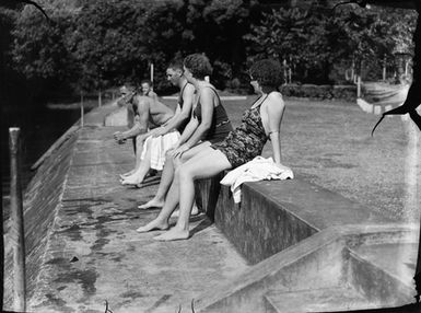 [Swimmers sitting on wall along waterfront]