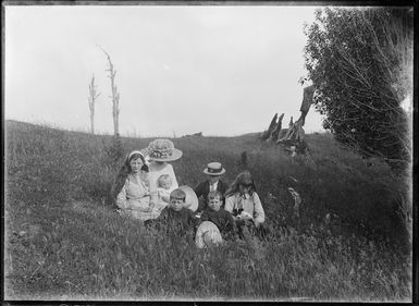 Unidentified woman sitting with her children on the grass