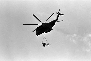 Bottom left side view of a CH-53 Sea Stallion helicopter assigned to Marine Heavy Helicopter Squadron 265 (HMH-265) transporting an M101 105 mm howitzer assigned to Charlie Battery, 1ST Battalion, 12th Marines, during Operation KERNEL BLITZ