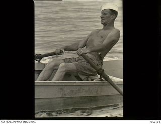 NEAR TOROKINA, BOUGAINVILLE ISLAND, SOLOMON ISLANDS. C. 1945-03-01. LEADING AIRCRAFTMAN C. W. KELLY OF LORNE, VIC, A FORMER PROFESSIONAL FISHERMAN, ROWING OUT TO SEA TO CATCH FISH FOR THE RAAF MEN ..