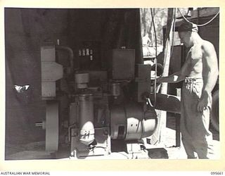 BOUGAINVILLE. 1945-08-30. STAFF SERGEANT H.S. CULLY, 2/4 ARMOURED REGIMENT WORKSHOP CHECKING THE LESTER BLACKSTONE GENERATOR, THE POWER SUPPLY FOR THE WORKSHOPS