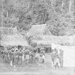 People and native constables standing around a man sitting at a desk, New Guinea, c1924 to ?