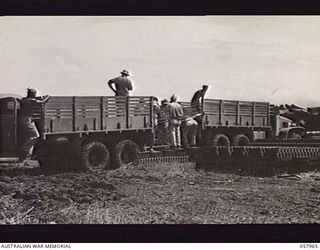 LAE, NEW GUINEA. 1943-10-04. UNITED STATES ARMY WRECKING PARTY LOADING A TRUCK WITH METAL AIRSTRIP MATTING