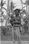 Man holds infant, basket hangs from man's shoulder