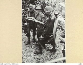 NEW GUINEA. 20 DECEMBER 1943. OFFICERS OF 29TH/46TH BATTALION AND 2/6TH FIELD REGIMENT DISCUSS DETAILS OF OPERATIONS USING A MAP PRIOR TO THE MILITIA ADVANCE AGAINST JAPANESE STRONGPOSTS NORTH OF ..