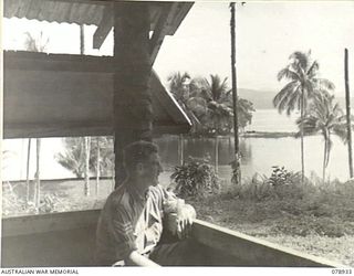 JACQUINOT BAY, NEW BRITAIN. 1945-02-04. NX174918 SERGEANT R.F. MURRAY ENJOYING THE VIEW FROM THE VERANDAH OF THE NEW YOUNG MEN'S CHRISTIAN ASSOCIATION AUSTRALIAN COMFORTS FUND SERVICES CLUB AT ..