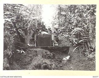 BOUGAINVILLE. 1945-05-24. CORPORAL WALKER, 58 CORPS FIELD PARK COMPANY ROYAL AUSTRALIAN ENGINEERS (1), USING A BULLDOZER TO BREAK DOWN THE ESCARPMENT ALONG THE USO-OSO ROAD TO ALLOW SUPPLIES AND ..