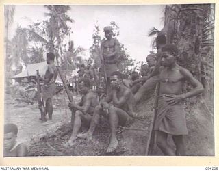 OINYALIB, NEW GUINEA. 1945-07-15. NATIVES OF 2 NEW GUINEA INFANTRY BATTALION, WATCHING THE WHITE MAN'S "SING-SING" DURING A CONCERT PRODUCED BY MEMBERS OF NO. 5 DETACHMENT, FIRST ARMY ENTERTAINMENT ..