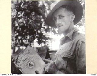 DUGUMUR, NEW GUINEA. 1944-07. VX81112 LIEUTENANT G.H. ATKINSON, MC, PLATOON COMMANDER, 57/60TH INFANTRY BATTALION, 15TH INFANTRY BRIGADE, HOLDS A CERTIFICATE ISSUED BY THE "HARDNBOLD RACING CLUB" ..