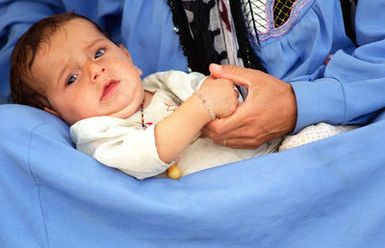 A Kurdish infant relaxes in his mother's lap as Kurdish evacuees from northern Iraq wind down from their long trip to Andersen Air Force Base, Guam, during Operation PACIFIC HAVEN. The operation, a joint humanitarian effort conducted by the US military, entails the evacuation of over 2,400 Kurds from northern Iraq to avoid retaliation from Iraq for working with the US government and international humanitarian agencies. The Kurds will be housed at Andersen AFB, while they go through the immigration process for residence in the United States