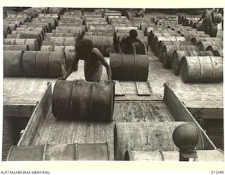 MILNE BAY, NEW GUINEA. 1944-04-04. NATIVES ROLLING 44 GALLON DRUMS CONTAINING 80 OCTANE MOTOR SPIRIT ON A UNITED STATES ARMY TRUCK AT THE 2ND AUSTRALIAN BULK PETROLEUM STORAGE COMPANY FOR SUPPLY TO ..