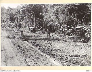 WEWAK AREA, NEW GUINEA. 1945-06-27. A LONG SHOT OF THE BIG ROAD. ENGINEERS ARE WORKING BESIDE AN 8 DIVISION TRUCK THAT WAS CAPTURED BY THE JAPANESE DURING THE FALL OF SINGAPORE AND BROUGHT TO NEW ..