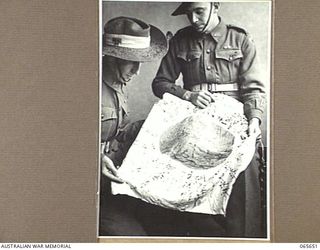 MELBOURNE, VIC. 1944-04-19. A JAPANESE FLAG CAPTURED BY MEMBERS OF THE 2/12TH INFANTRY BATTALION AT FINSCHHAFEN ON THE 2ND OCTOBER, 1943, DISPLAYED BY GUNNER PARKER, LEFT (1) AND GUNNER TOWNSEN (2)