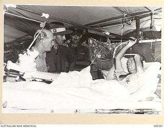 JACQUINOT BAY, NEW BRITAIN. 1945-04-08. DURING A VISIT TO 105 CASUALTY CLEARING STATION SENATOR J.M. FRASER, ACTING MINISTER FOR THE ARMY (1), SPEAKS WITH PRIVATE R.A. LEDDY (4), WHO WAS WOUNDED IN ..