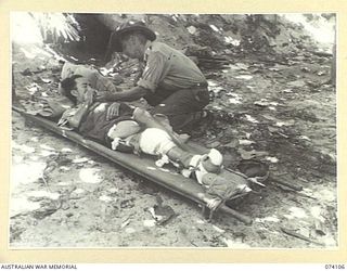 HANSA BAY, NEW GUINEA. 1944-06-16. QX24902 SERGEANT E. SMITH, 4TH INFANTRY BRIGADE (1), GIVING QUAN YIM (2) A CIGARETTE. QUAN YIM BROKE HIS LEG WHILE A PRISONER OF THE JAPANESE. HE WAS ONE OF THE ..