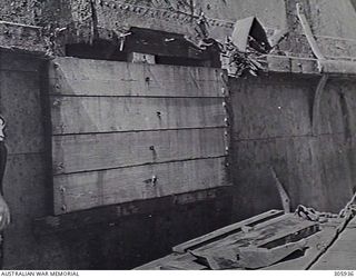 PORT HERVEY, PAPUA. 1943-05-09. MAKESHIFT REPAIRS TO BOMB DAMAGE TO THE SIDE PLATING OF THE MERCHANT VESSEL NOORA, DAMAGED BY JAPANESE AIR ATTACK. (NAVAL HISTORICAL COLLECTION)