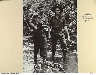 FINSCHHAFEN AREA, NEW GUINEA. 1943-11-19. ON A WATERLOGGED TRACK DEPARTMENT OF INFORMATION CAMERAMAN FRANK BAGNALL AND PHOTOGRAPHER NORMAN BROWN EN ROUTE TO A FORWARD AREA