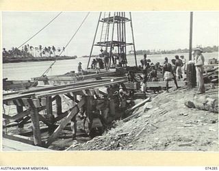 MADANG, NEW GUINEA. 1944-06-26. TROOPS OF THE 2/4TH FIELD SQUADRON AND NEW GUINEA NATIVES WORKING ON THE CONSTRUCTION OF A NEW LIBERTY SHIP WHARF