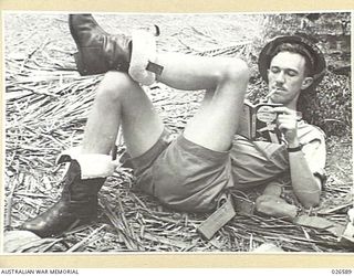 PILOT OFFICER L. CHIPPENDALL, A PILOT OF THE BEAUFORT TORPEDO SQUADRON, RAAF, RELAXES OFF DUTY WITH A "WHODUNIT"