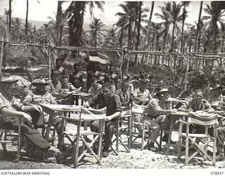 JACQUINOT BAY, NEW BRITAIN. 1945-02-04. AUSTRALIAN SERVICE PERSONNEL RELAXING IN THE SUNNY QUADRANGLE OF THE NEW YOUNG MEN'S CHRISTIAN ASSOCIATION AUSTRALIAN COMFORTS FUND SERVICES CLUB AT ..