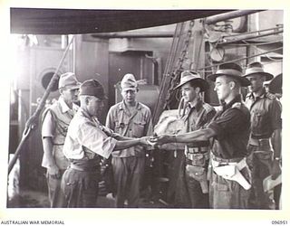 BOUGAINVILLE, 1945-09-18. MAJOR GENERAL K. KIJIMA HANDING HIS SWORD TO CAPTAIN W. DAVIES ABOARD THE DEBORAH IN NUMA NUMA HARBOUR. THE SWORD WAS ACCEPTED ON BEHALF OF LIEUTENANT GENERAL S.G. SAVIGE, ..