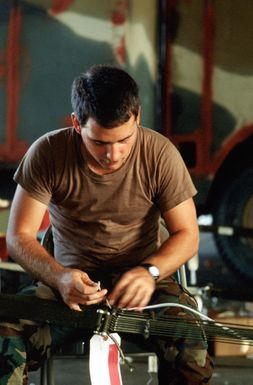 A1C Donald Popp, 8th Mobile Aerial Port Squadron, repairs suspension lines on parachute prior to attaching packages to be delivered during Christmas Drop. The annual airdrop is a humanitarian effort providing aid to needy islanders throughout Micronesia during the holiday season