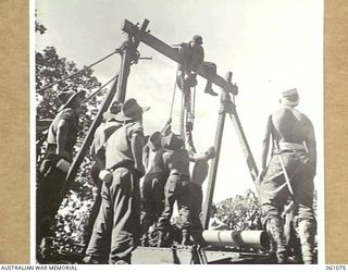 FINSCHHAFEN AREA, NEW GUINEA. 1943-11-04. MEMBERS OF THE 4TH AUSTRALIAN FIELD BAKERY ERECTING SHEER LEGS ON AN AMPHIBIOUS "DUKW" IN PREPARATION FOR UNLOADING THE NEW OVENS FOR THE NEW BAKERY