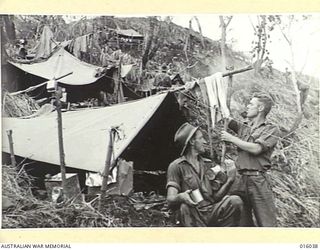 NEW GUINEA. UPPER RAMU VALLEY ADVANCE. 1 NOVEMBER 1943. AT AN ADVANCED POST PTE. J. SMALL OF PERTH, WEST AUSTRALIA, W/ O.B. TAYLOR OF VICTORIA PARK, WEST AUSTRALIA WITH TIN RATIONS. (NEGATIVE BY G. ..