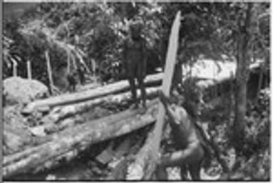 Bridge-building: men split logs for planking