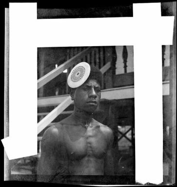 Man with a kapkap in his hair, standing in front of a verandah, Rabaul, New Guinea, ca. 1936, 2 / Sarah Chinnery