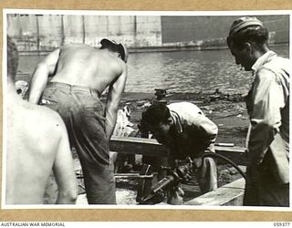 LAE, NEW GUINEA, 1943-11-05. TROOPS OF THE 1052ND ENGINEERS PORT CONSTRUCTION AND REPAIR GROUP, UNITED STATES ARMY USING A PORTABLE AIR DRIVEN SAW DURING THE CONSTRUCTION OF THE FIRST LIBERTY DOCK