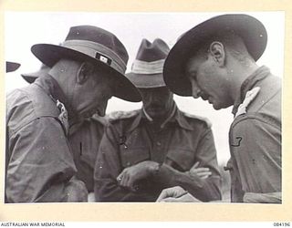 SUAIN PLANTATION, NEW GUINEA. 1944-12-10. MAJOR-GENERAL J.E.S. STEVENS, GENERAL OFFICER COMMANDING 6 DIVISION, STUDIES PATROL REPORTS WITH BRIGADIER J.E.G. MARTIN, 19 INFANTRY BRIGADE, (2), AND ..