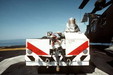 A crash crewman wearing a fire fighting suit stands by in a damage control vehicle on the flight deck of the amphibious assault ship USS GUAM (LPH 9). The ship is participating in operations off the coast of Lebanon