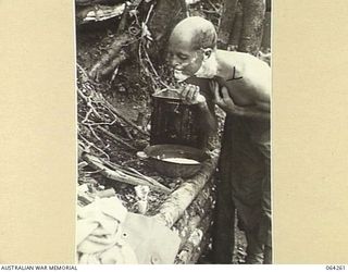 FINISTERRE RIDGES, NEW GUINEA. 1944-01-23. QX17774 CORPORAL C. BUTCHART OF "A" COMPANY, 2/9TH INFANTRY BATTALION HAVING A SHAVE DURING A LULL IN THE BATTLE FOR SHAGGY RIDGE