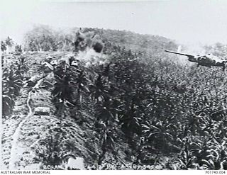 Boram, Wewak, New Guinea. 1944-10-16. Aerial photograph of a Mitchell B25 bomber aircraft of the United States Army Air Force dropping bombs over Japanese anti-aircraft positions on the ridge near ..