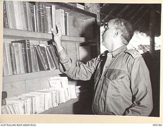 AITAPE, NEW GUINEA. 1945-03-29. JEMADAR (2ND LIEUTENANT) NAN SINGH, 5/2 PUNJAB REGIMENT, AN INDIAN OFFICER RELEASED FROM THE JAPANESE BY AUSTRALIAN TROOPS, CHOOSES A BOOK FROM THE LIBRARY IN THE ..