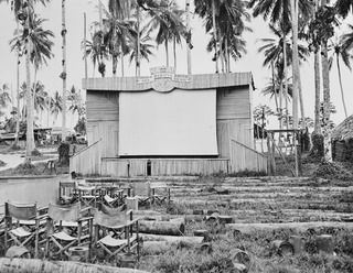 Astrolabe Bay, Madang, New Guinea, 1945-10-06. The open-air cinema at Headquarters, RAAF Northern Command (NORCOM). The stage, which has been built entirely out of the blunt ends of sago palms, is ..