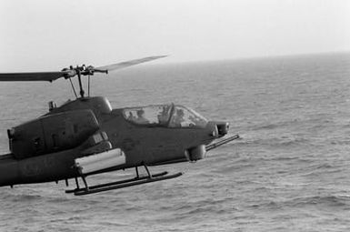 A right side view of an AH-1 Sea Cobra helicopter taking off from the amphibious assault ship USS GUAM (LPH 9) during Operation URGENT FURY