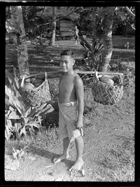 Unidentified boy carrying items in woven baskets, Samoa